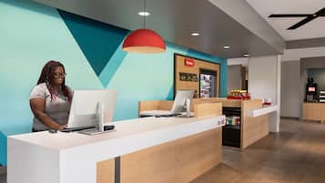 A modern reception desk with a computer, a customer service area, and a visible kitchen in the background.