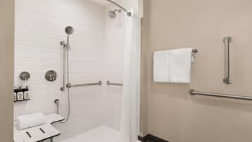 A modern bathroom with a shower, grab bars, a sink, and a towel rack.