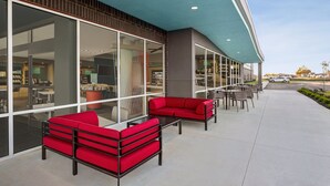 Un edificio moderno con amplios ventanales, asientos exteriores rojos y una vista despejada del interior.