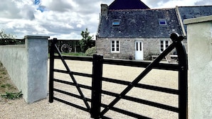 Un bâtiment en pierre avec un toit sombre, une porte blanche et une fenêtre.