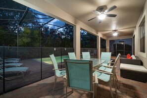 Une terrasse extérieure dotée d’une véranda en verre, d’une piscine et de différents espaces pour s’asseoir.
