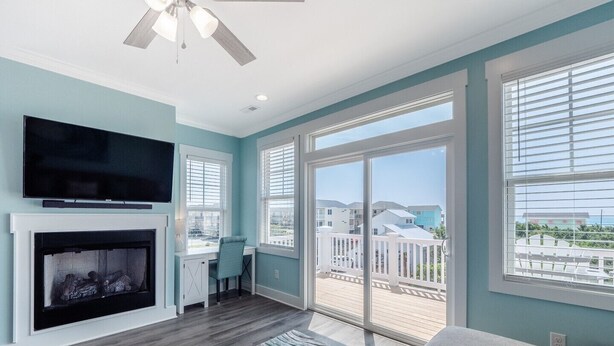 A living room with a fireplace, a television, and a balcony with a view of the neighborhood.