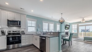 A modern kitchen with white cabinets, stainless steel appliances, and a large island.
