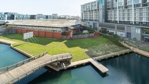A modern building with a flat roof, a grassy area, and a dock extending into a body of water. - Spacious Studio Apartment on the Canals in CT (Cape Town)