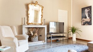 Una sala de estar con chimenea, televisor, sofá y un espejo decorativo.