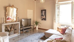 Una sala de estar con chimenea, televisor, sofá y un espejo grande.