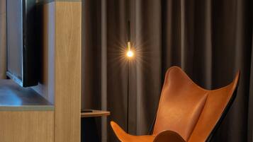 Una habitación moderna con un armario de madera, un televisor, una lámpara de pie y un sillón de cuero.