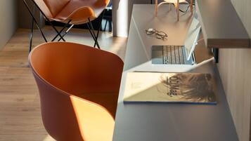 Un espacio de trabajo moderno con un escritorio, una computadora portátil y un par de lentes.