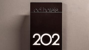 Un cartel negro con la inscripción "od hotels" y el número "202" sobre un fondo liso.