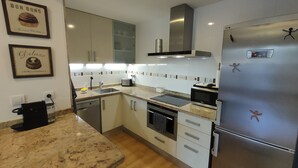A modern kitchen with white cabinets, a stainless steel refrigerator, a built-in oven, and a microwave. - NON STRESS Arena Beachfront (Alboraya)
