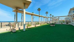 A rooftop terrace with artificial grass, palm trees, and a clear view of the beach. - NON STRESS Arena Beachfront (Alboraya)