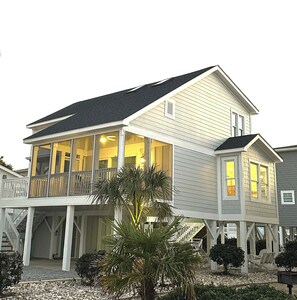A two-story house with a balcony, a covered porch, and a small deck area. - Bucket List Beach Retreat, Sunset Beach - with EV Charger 
HGTV WINNER! (Sunset Beach)