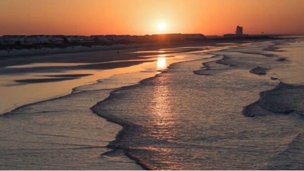 Une rivière qui traverse une zone côtière au coucher du soleil.