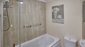 A modern bathroom with a glass-enclosed shower, a white bathtub, and a toilet. - The Garden Flat (Darlington)