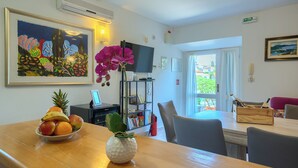 A dining area with a wooden table, a fruit bowl, a potted orchid, and a television on a stand. - Villa Bonaca - Three Bedroom Villa, Sleeps 6 (Sumartin)