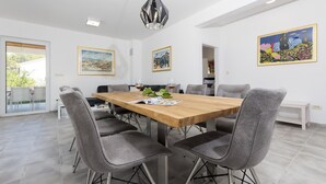 Un espace de salle à manger moderne avec une table en bois, des chaises à revêtement gris et un luminaire suspendu.