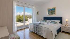Une chambre à coucher avec un grand lit, une table de chevet, une lampe et une vue sur l’extérieur grâce à une porte coulissante.