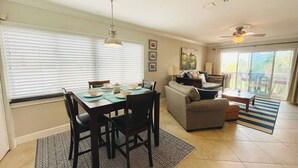A dining area with a table set for four, a sofa, and a ceiling fan.
