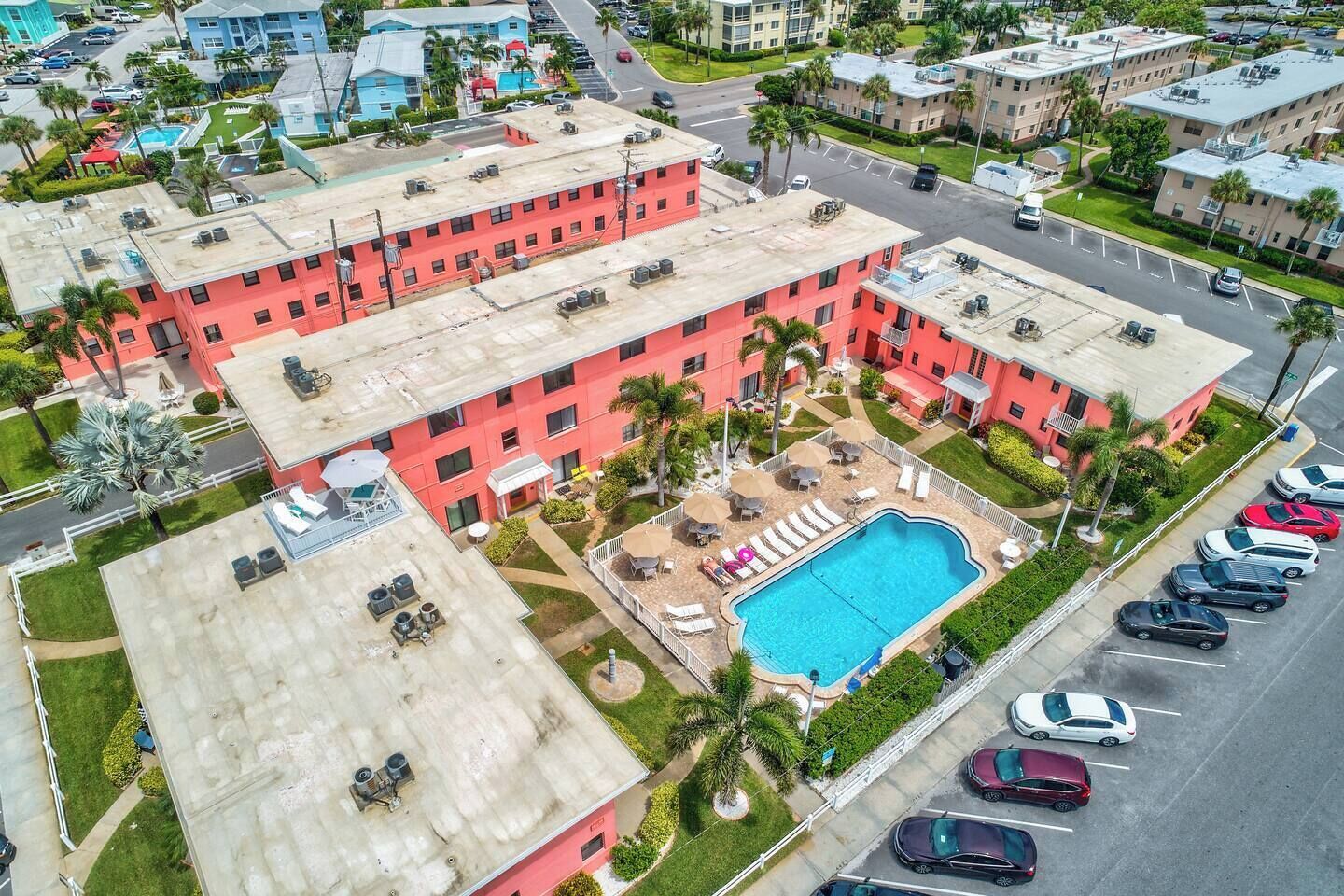 A multi-story hotel with a rooftop pool, outdoor seating, and a parking lot.