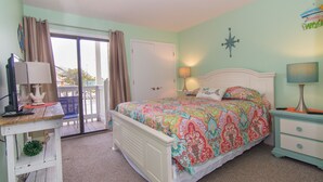 A bedroom with a bed, a desk, and a dresser. - Seaside Escape in Pebble Beach  (Emerald Isle)
