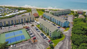 A coastal hotel with multiple buildings, a parking lot, and a tennis court. - Seaside Escape in Pebble Beach  (Emerald Isle)