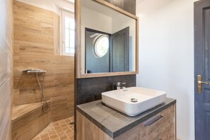 Ein Badezimmer mit einem Holzlagerflächen-Schrank, einem weißen Waschbecken und einer Dusche mit Glastür.