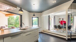 Una cocina moderna con una isla grande, un comedor con una silla roja y vistas al exterior.
