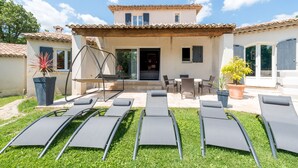 Una casa con un patio, mobiliario exterior y una hamaca.