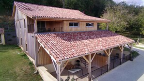 Uma casa de madeira de dois andares com telhado de telhas vermelhas e varanda coberta.