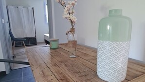 A wooden dining table with a glass vase and a decorative bottle, a chair, and a mirror on the wall.