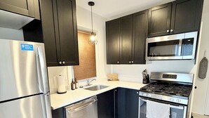 Uma cozinha moderna com armários escuros, eletrodomésticos de aço inoxidável, micro-ondas e fogão a gás.