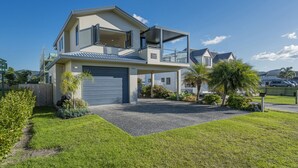 Ein modernes, zweistöckiges Haus mit Garage, überdachter Veranda und gepflegtem Rasen.
