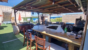An outdoor patio with a wooden table, chairs, and a barbecue area. - This Venue is set up for hourly rates only. 4.5 hour min.  Capacity 150 guests   (Costa Mesa)