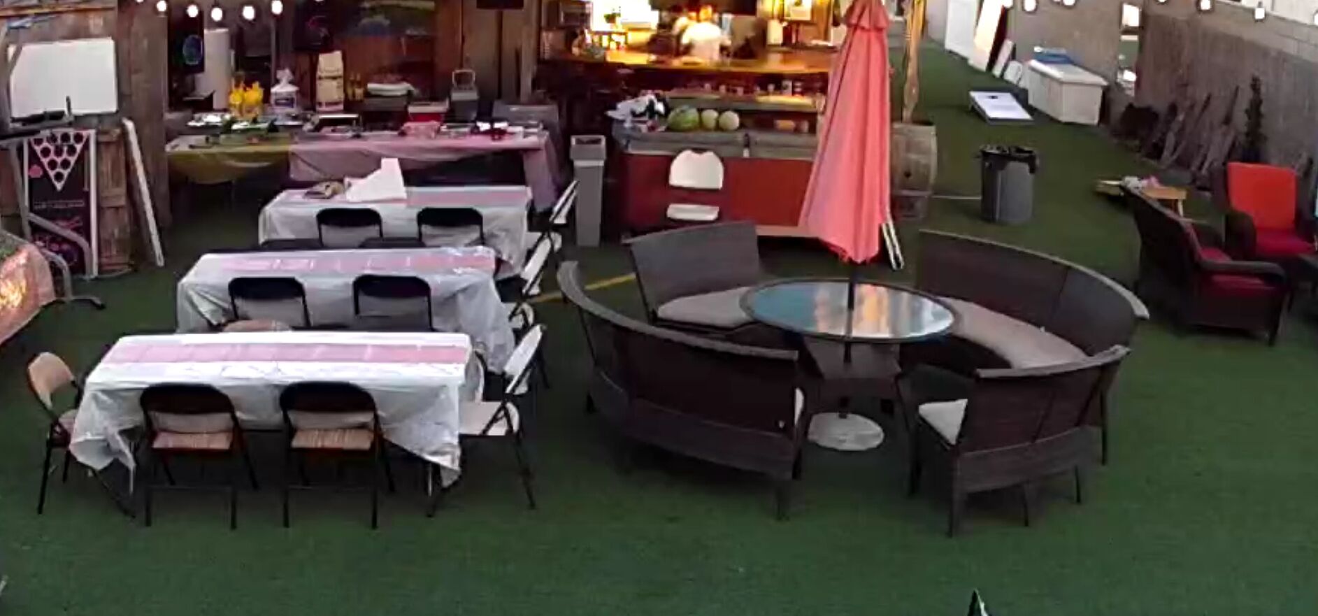 Un espace extérieur aménagé avec des tables et des chaises rondes, protégé par des parasols et entouré de verdure.