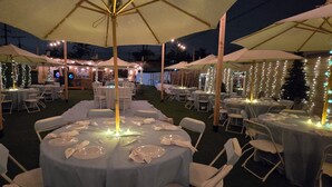 An outdoor dining area with round tables, white chairs, and umbrellas. - This Venue is set up for hourly rates only. 4.5 hour min.  Capacity 150 guests   (Costa Mesa)
