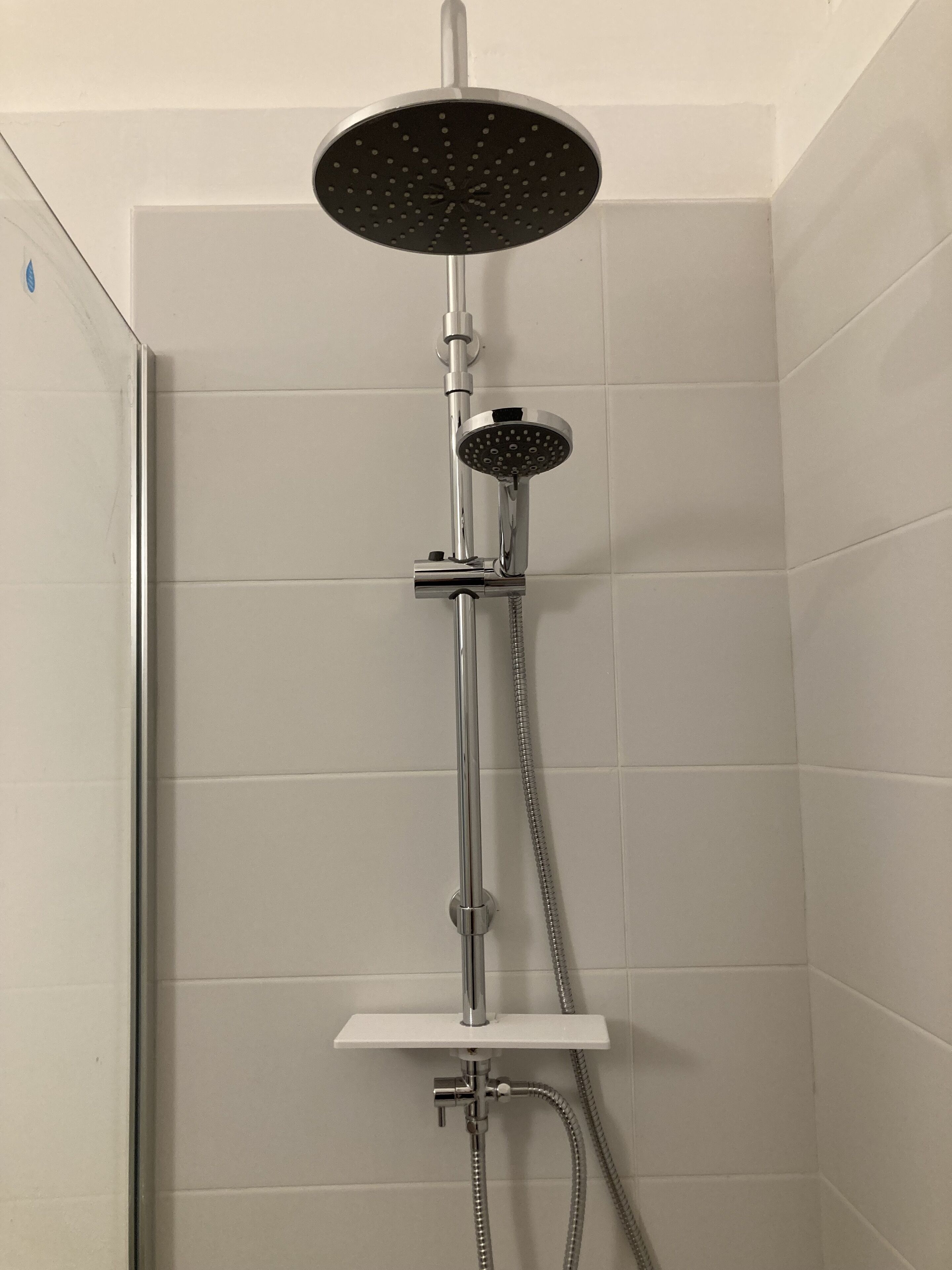 Ducha con cabezal de ducha de mano y otro fijo montado en la pared.