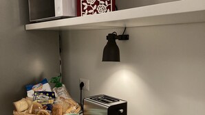 Una encimera de cocina con un tostador, botes de mermelada, una taza y una cesta de pan.