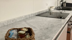 Una cocina moderna con encimera de mármol, un lavamanos y una cesta de frascos.