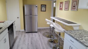 A kitchen with a stainless steel refrigerator, white bar stools, and a countertop with a sink. - In the Heart of Longmont ~ 15 Minutes to Boulder, Colorado (Longmont)