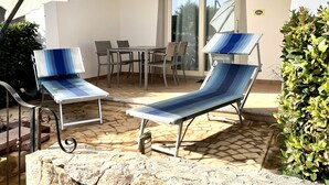 A patio with two lounge chairs, a table, and a covered seating area. - Mediterranean&sea Shell House (Limpiddu)