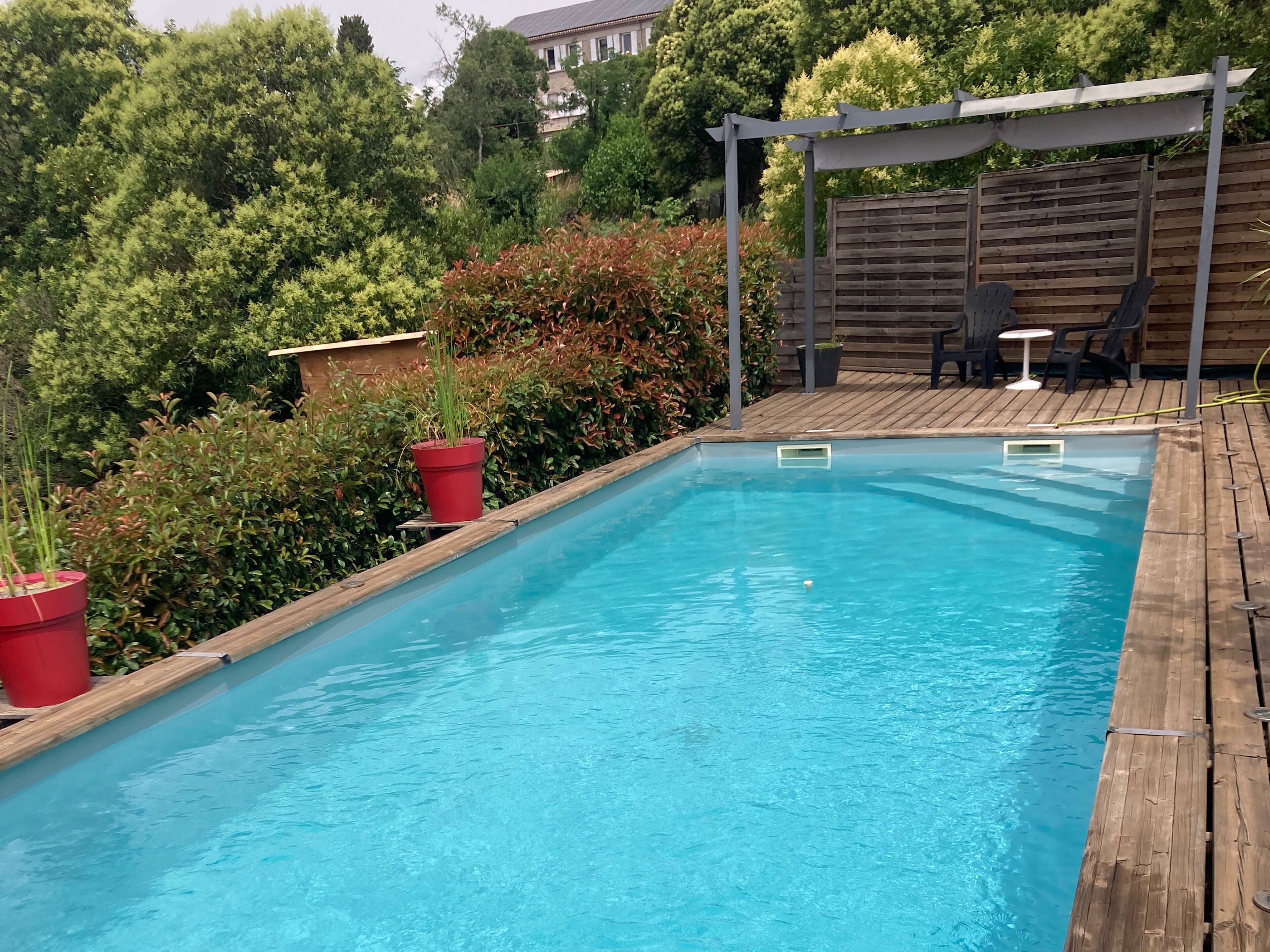 En rektangulär pool med ett trädäck och en pergola.