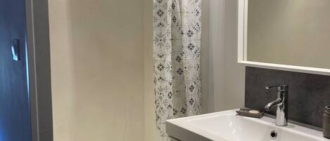 A bathroom with a shower, a sink, and a mirror.