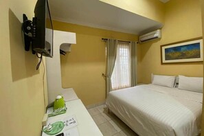 Ein Hotelzimmer mit Bett, Schreibtisch mit Telefon, Klimaanlage und einem Bild an der Wand.