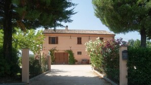 Une maison à deux étages, avec un toit recouvert de tuiles, une porte d’entrée et une allée menant à l’entrée.