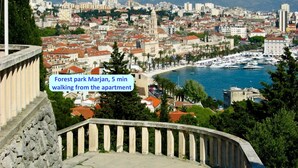 A coastal cityscape with a view of the sea, a marina, and a forest park called Marjan.