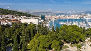 A coastal town with a marina, dense greenery, and a rocky coastline.