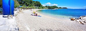 A beach with pebbles, people sunbathing, and a clear blue sea. - Lovely Studio Apartment in the Perfect Location (Split)