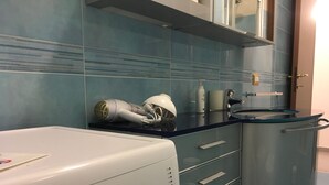 A modern kitchen with a built-in washer and dryer, a stainless steel sink, and a glass cabinet. - Appartamento Le Campane (Verona)
