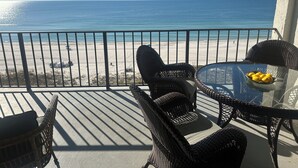 Ein Balkon mit Korbmöbeln und einem Tisch mit Zitronen, mit Blick auf einen Strand und das Meer.