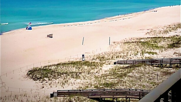 Ein Strand mit blauem Himmel, ruhiger See und sandigem Ufer.